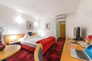 a hotel room with a bed and a desk with a laptop at Hotel Boltzmann in Vienna