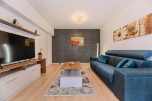 a living room with a blue couch and a flat screen tv at Luxury Landing Apartments Complex Qualis Brasov in Braşov