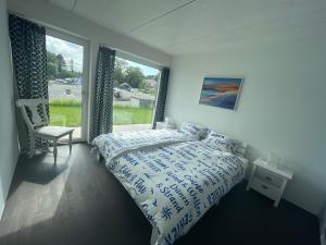 a bedroom with a bed and a chair and a window at Leben im Hafen am idyllischen Murtensee in Guévaux
