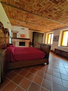 1 dormitorio con cama con sábanas rojas y chimenea en Cascina Flino - Tra le vigne - Appartamento 2, en Alba