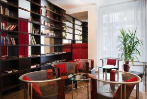 a room with chairs and tables and a book shelf at Hotel Boltzmann in Vienna