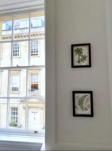a wall with two pictures on a wall with a window at Exclusive Georgian apartment in centre of Bath in Bath