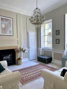 a living room with a chandelier and a fireplace at Exclusive Georgian apartment in centre of Bath in Bath