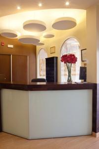 a lobby with a counter with a vase of red roses at Hotel Quino in Guardamar del Segura