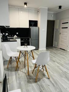 a kitchen with a table and two white chairs at Apartment Comfort in Bartoszyce