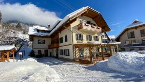 a house in the snow with snow piled up at Gästehaus Rader in Weissbriach