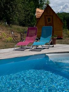 two chairs sitting on a deck next to a swimming pool at Insolite avec piscine Au Bonheur Comtois in Ronchamp