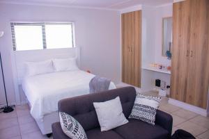 a living room with a bed and a couch at Charms and bows studio apartment -near ORT airport in Boksburg