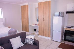 a small living room with a couch and a refrigerator at Charms and bows studio apartment -near ORT airport in Boksburg