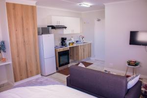 a small kitchen with a couch and a refrigerator at Charms and bows studio apartment -near ORT airport in Boksburg