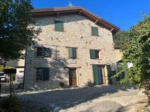 una antigua casa de piedra con persianas verdes en Antico Borgo le Roste en Sassomorello