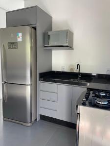 Il comprend une cuisine équipée d'un réfrigérateur en acier inoxydable et d'une cuisinière. dans l'établissement Casa 3 quartos Bombinhas lado Mar ou AP de 2 quartos, à Bombinhas
