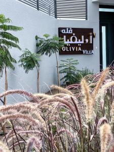 a sign on the side of a building with plants at Olivia Chalet فلة أوليفيا in Al ‘Aqar
