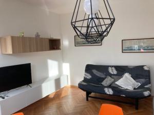 uma sala de estar com um sofá preto e uma televisão em Casa dei Gelsomini em Trieste
