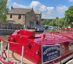 a red boat is docked in front of a building at The Clock Tower Skipton High Street. Nothing Average Here! in Skipton