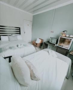 ein weißes Schlafzimmer mit 2 Betten und einem TV in der Unterkunft Thokazi Haven Guest House & Backpacker in Majomela