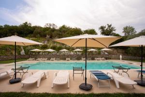 - une piscine avec des chaises, des tables et des parasols dans l'établissement Il Paesaggio Lunare, à Aliano