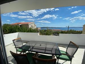 un patio con tavolo in vetro e sedie sul balcone. di Apartman Mila a Kaštela (Castelli)