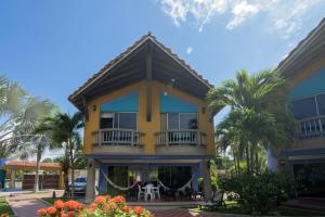 Maison jaune avec balcon et palmiers dans l'établissement Cabaña Playa Caimán 1, à Coveñas