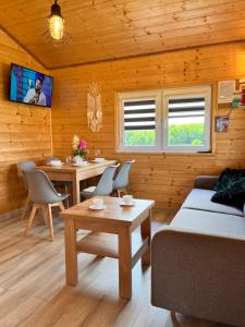 ein Wohnzimmer mit einem Sofa, Tischen und einem TV in der Unterkunft Domki u Iwony in Kudowa-Zdrój