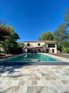 an image of a swimming pool in front of a house at La Maison L'Eperon, stylish 5 star villa surrounded by vineyard near Saint Emilion in Vérac