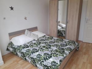 ein Schlafzimmer mit einem Bett und einem Spiegel in der Unterkunft LES LILAS in Les Lilas