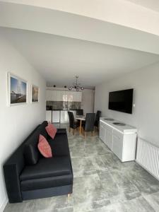 uma sala de estar com um sofá preto e uma mesa em Apartament Baltic Korona B20 em Darłowo