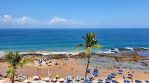 a beach with people with umbrellas and the ocean at Farol Barra Flat in Salvador