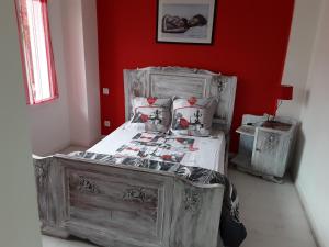 Ce lit se trouve dans une chambre dotée d'un mur rouge. dans l'établissement La Maison du Monde, à Limoges