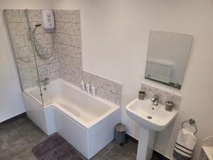 a bathroom with a shower and a tub and a sink at Bracken Dene in Lynemouth