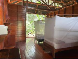 1 dormitorio con 2 camas en una habitación con paredes de madera en Tambopata Edosikiana Lodge, en Tambopata