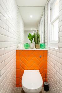 baño con aseo y pared de color naranja y blanco en Beautiful, central, 3 min walk from beach, 2 King doubles en Brighton & Hove