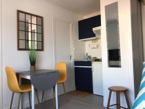 a small kitchen with a table and yellow chairs at Appt FOURAS Centre Ville 50m de la Mer in Fouras