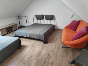 a bedroom with two beds and an orange chair at Attic Apartment in Piešťany