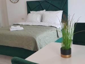 Un dormitorio con una cama y una mesa con un jarrón. en Grey Residence Apartments en Tunari