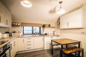 cocina con armarios blancos y mesa de madera en No.70 en Bayble