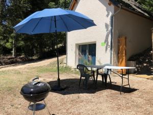 a grill and a blue umbrella next to a table and a grill at STUDIO SYMPA et AU CALME in Le Chambon-sur-Lignon