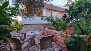 un patio con sillas, una mesa y una pared de ladrillo en Vita Apartament en Ksamil