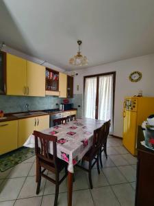 a kitchen with a table and chairs and a kitchen with yellow cabinets at Casa Andrè in Pescantina