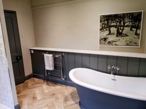 a bathroom with a tub and a painting on the wall at Stunning New Forest Cottage close to Paultons Park in Ower