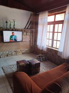 Pousada Canto da Praia في ساو بيدرو دا ألديا: غرفة معيشة مع أريكة وتلفزيون بشاشة مسطحة