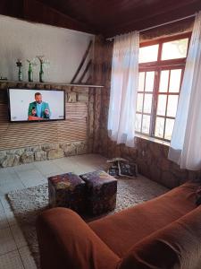 a living room with a couch and a flat screen tv at Pousada Canto da Praia in São Pedro da Aldeia