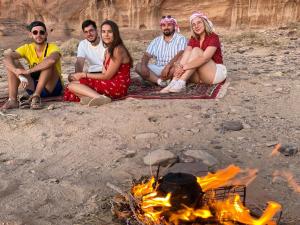 Un groupe de personnes assises autour d'un feu de camp dans l'établissement Moon city camp, à Wadi Rum