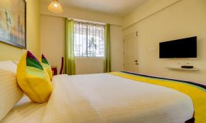 a bedroom with a large white bed and a flat screen tv at Itsy Hotels Ushodaya Royal Residency in Trivandrum