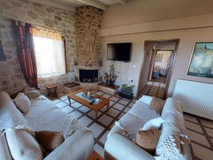 a living room with two white couches and a fireplace at Eftihia's Home in Agia Triada