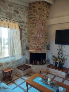 Eftihia's Home في Agia Triada: غرفة معيشة مع موقد حجري وتمثال لامرأة