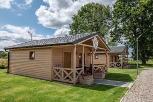 une cabane en bois avec une terrasse couverte sur une pelouse dans l'établissement Osada Trzy Siostry, à Pobierowo