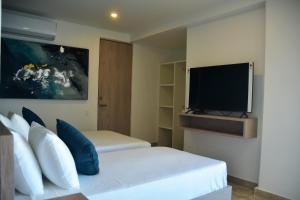een slaapkamer met een bed en een flatscreen-tv bij Rentas Vacacionales Torre Diez in Playa del Carmen
