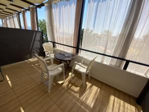 einen Balkon mit weißen Stühlen, einem Tisch und Fenstern in der Unterkunft Rafaella's Maisonette at Rafaella Resort in Kokóni