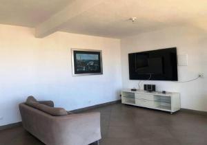 a living room with a couch and a flat screen tv at Cristal casa de vidro in São Thomé das Letras